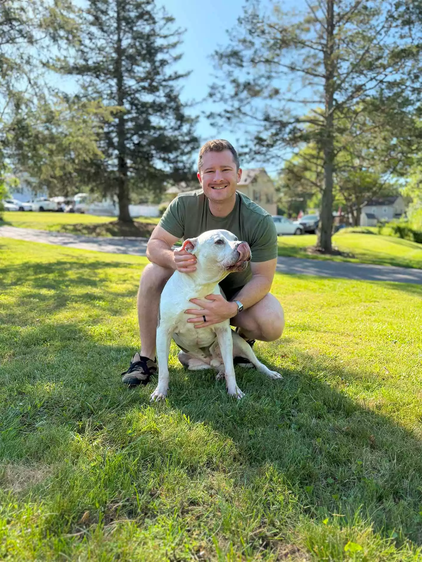 Tom Farrell, owner of Poop Daddy, holding his dog Micky in a professionally cleaned yard